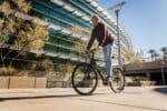 man in red long sleeve shirt and blue denim jeans riding on bicycle